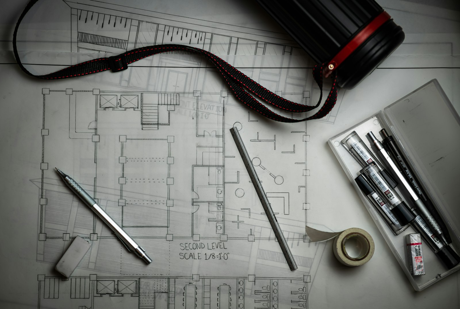 Planos arquitectónicos y herramientas de dibujo sobre una mesa